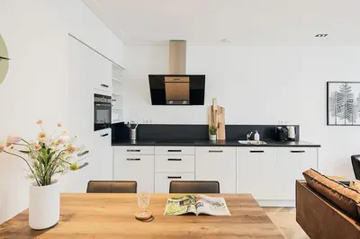 a kitchen with white cabinets and a wooden table at Damrak Short Stay Amsterdam in Amsterdam