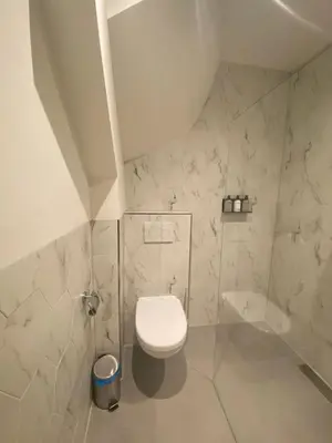 a bathroom with a white toilet and marble walls at Damrak Short Stay Amsterdam in Amsterdam