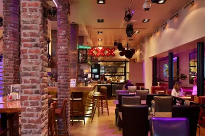 a restaurant with a brick wall and tables and chairs at Damrak Short Stay Amsterdam in Amsterdam