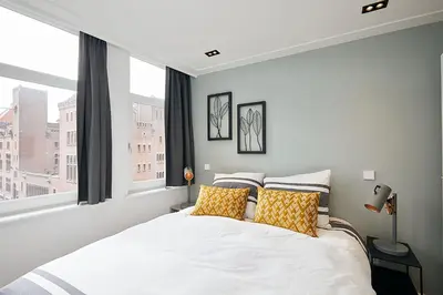 a bedroom with a large white bed with yellow pillows at Damrak Short Stay Amsterdam in Amsterdam