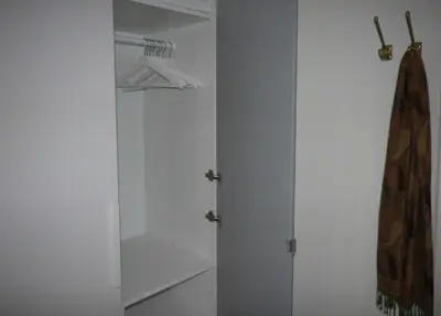 a white closet with a white door and a robe at B&B Mondriaan in Amsterdam