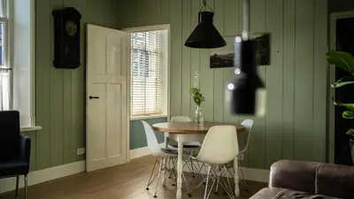 a dining room with green walls and a table and chairs at Traditional family apartment with garden at countryside Amsterdam in Landsmeer