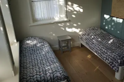 two beds in a room with a window and a table at Traditional family apartment with garden at countryside Amsterdam in Landsmeer