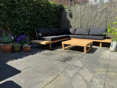 a black couch and a coffee table on a patio at Traditional family apartment with garden at countryside Amsterdam in Landsmeer