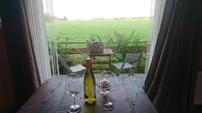 a wooden table with a bottle of wine and glasses at B&B ZusenZomer in Oostwoud