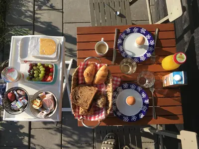 a picnic table with breakfast foods and eggs on it at B&B ZusenZomer in Oostwoud