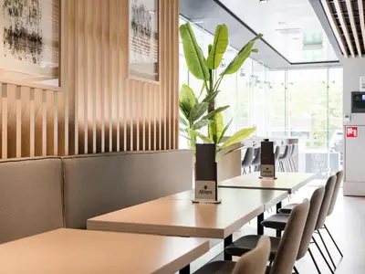 a row of tables in a restaurant with a potted plant at Executive Residency by Best Western Amsterdam Airport in Hoofddorp