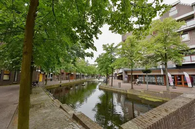 a canal in the middle of a city with buildings at Bed & Ontbijt Haddock in Almere
