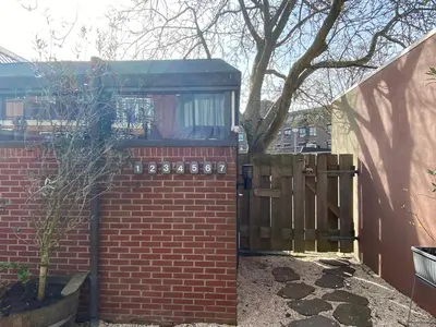 a brick fence with a wooden gate in a yard at Bed & Ontbijt Haddock in Almere