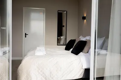 a bedroom with a white bed with a mirror at Grand Central Suites in Zandvoort