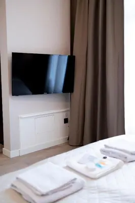 a flat screen tv sitting on a wall with towels at Grand Central Suites in Zandvoort
