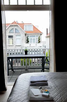 a bedroom with a bed and a view of a balcony at Grand Central Suites in Zandvoort