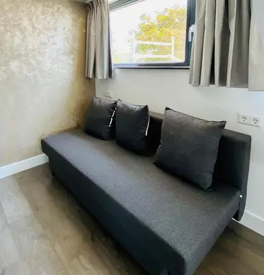 a couch sitting in a room with a window at Duinzand in Noordwijk aan Zee