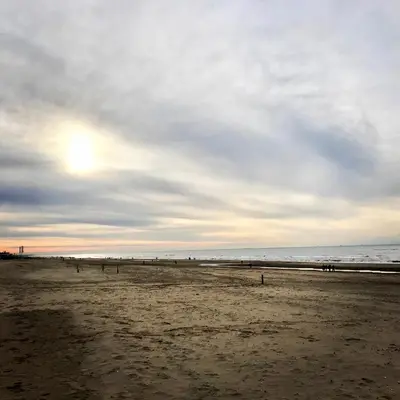 a beach with people on the sand and the ocean at Duinzand in Noordwijk aan Zee