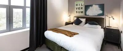 a bedroom with a large bed with white sheets and pillows at Hilversum City Apartments in Hilversum