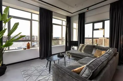 a living room with a couch and large windows at Hilversum City Apartments in Hilversum