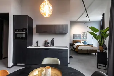 a kitchen with a table and a room with a bed at Hilversum City Apartments in Hilversum