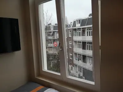 a bedroom window with a view of a building at RoomWest in Amsterdam