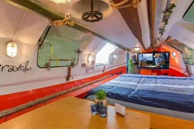 a room with a bed and a table in it at PolarStern - unique boatstay! in Monnickendam
