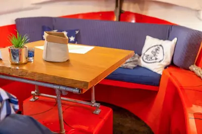 a table with a blue couch and a wooden table with a table sidx sidx at PolarStern - unique boatstay! in Monnickendam