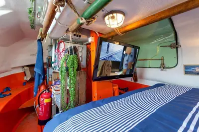 a room with a bed and a tv in a fire truck at PolarStern - unique boatstay! in Monnickendam