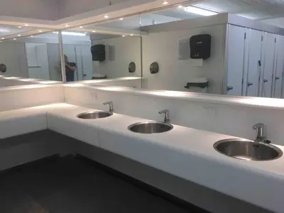 a public bathroom with three sinks and a mirror at PolarStern - unique boatstay! in Monnickendam