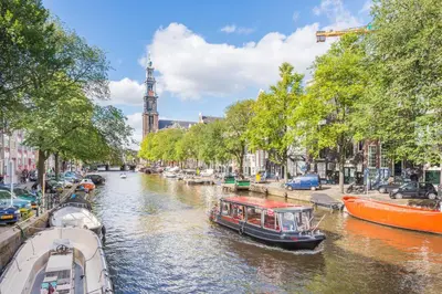 a boat traveling down a canal in a city at B&B 1971 Hazenstraat - Shared Bathroom in Amsterdam
