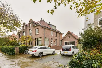 two cars parked in a parking lot in front of a house at Luxury Garden View Apartment in Zandvoort