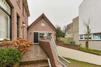 a brick house with a staircase leading to a door at Luxury Garden View Apartment in Zandvoort