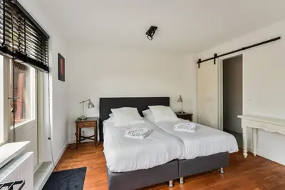 a bedroom with a large bed with white sheets at Luxury Garden View Apartment in Zandvoort