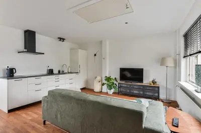 a living room with a couch and a kitchen at Luxury Garden View Apartment in Zandvoort