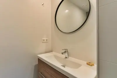 a bathroom with a sink and a mirror on the wall at Luxury Garden View Apartment in Zandvoort