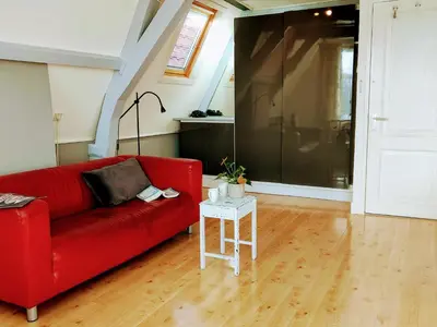 a red couch in a living room with a table at B&B Hart van Leiden in Leiden