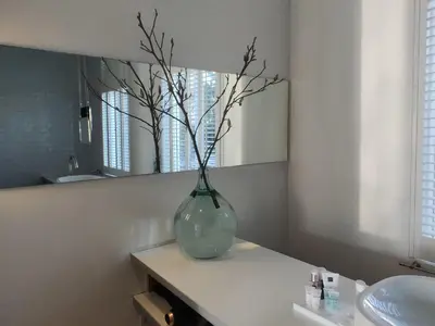 a vase with branches in it sitting on a counter in a bathroom at B&B Hart van Leiden in Leiden