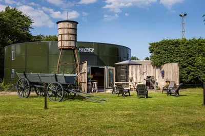 an old water tower and a wagon in front of a building at Bed&Bbq Longhornranch in Akersloot