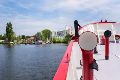 a boat tied up to a dock on a river at Lightship Amsterdam in Amsterdam