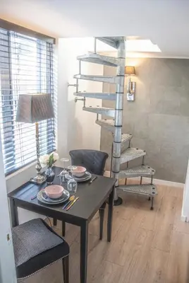 a dining room with a table and a spiral staircase at Tiny House Lindenhouse in Heemstede