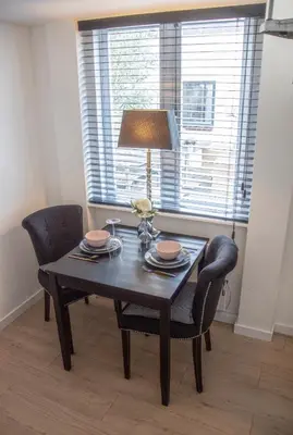 a dining room table with two chairs and a lamp at Tiny House Lindenhouse in Heemstede