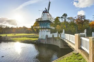 a bridge over a river with a windmill on it at Tiny House Lindenhouse in Heemstede