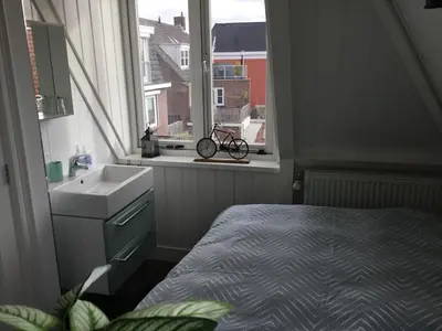 a bathroom with a bed and a sink and a window at B&B Alkmaars Toppunt in Alkmaar