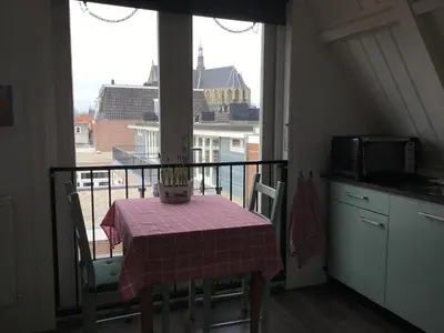 a kitchen with a table and a balcony with a view of a building at B&B Alkmaars Toppunt in Alkmaar