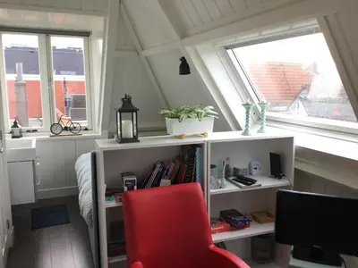 a red chair in a room with two windows at B&B Alkmaars Toppunt in Alkmaar