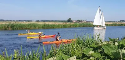 a group of people in kayaks on a river with a sailboat at Lake house 21 relax accommodation iR Sauna in Warmond