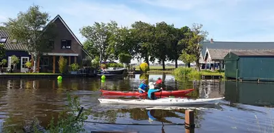 two people in kayaks on the water near a house at Lake house 21 relax accommodation iR Sauna in Warmond