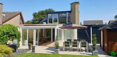 a house with a patio with an umbrella at Lake house 21 relax accommodation iR Sauna in Warmond