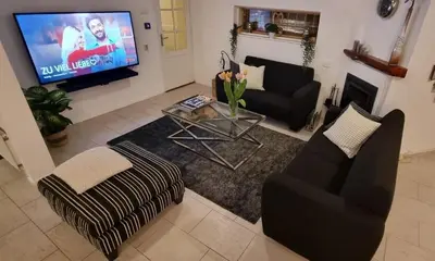 a living room with a tv and a couch and a table at Lake house 21 relax accommodation iR Sauna in Warmond