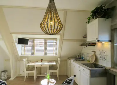 a kitchen with a table and a chandelier at Casa duna close to the beach, city centre, dunes and parking area in Zandvoort
