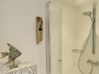 a shower with a glass door in a bathroom at Casa duna close to the beach, city centre, dunes and parking area in Zandvoort
