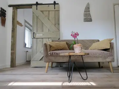 a living room with a couch and a table with a door at Casa duna close to the beach, city centre, dunes and parking area in Zandvoort