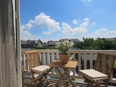 a table with two chairs and a potted plant on a balcony at Casa duna close to the beach, city centre, dunes and parking area in Zandvoort